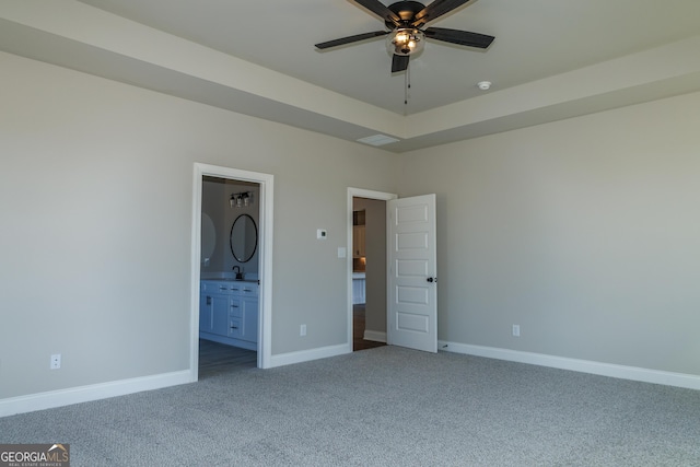 unfurnished bedroom featuring carpet floors, sink, ceiling fan, and ensuite bath