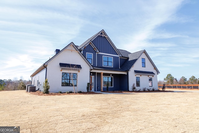 view of front of house with central AC unit and a front yard