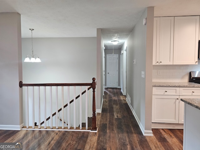 corridor with a textured ceiling and dark hardwood / wood-style floors