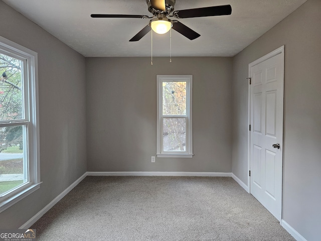 carpeted spare room featuring ceiling fan