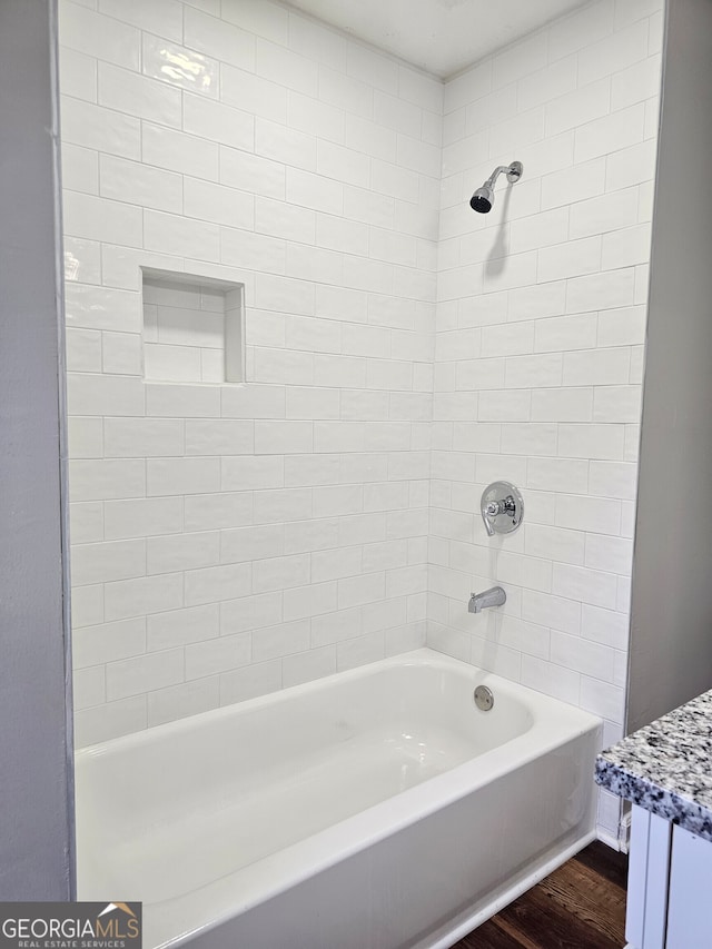 bathroom featuring hardwood / wood-style floors, tiled shower / bath, and vanity