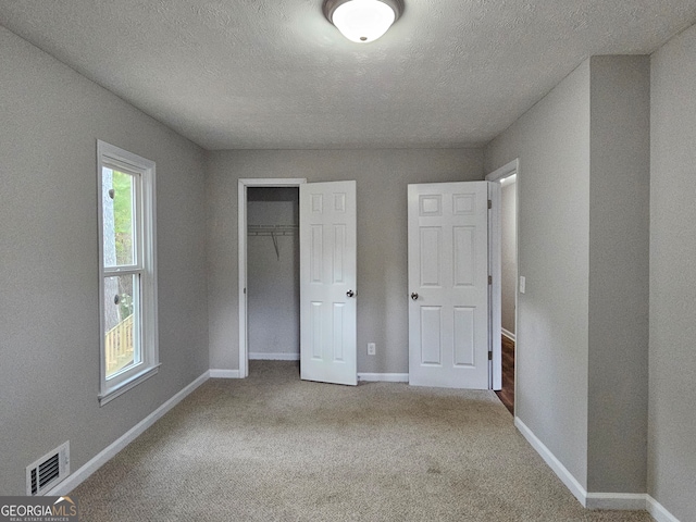 unfurnished bedroom with carpet, a textured ceiling, and a closet