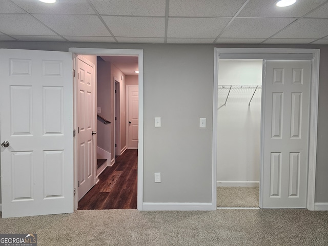 unfurnished bedroom with a closet, dark carpet, and a drop ceiling