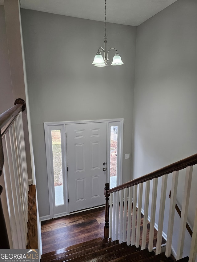 foyer featuring dark wood-type flooring, a chandelier, and plenty of natural light