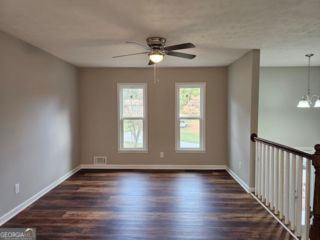 unfurnished room featuring dark wood-type flooring, a textured ceiling, and ceiling fan with notable chandelier