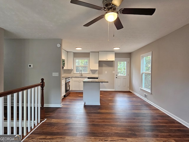 kitchen with stainless steel appliances, a center island, white cabinets, sink, and dark hardwood / wood-style floors