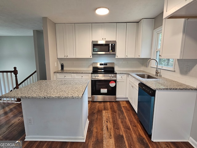 kitchen with white cabinetry, sink, appliances with stainless steel finishes, light stone countertops, and dark wood-type flooring