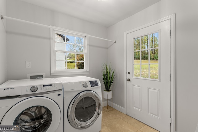 clothes washing area featuring a wealth of natural light, washer and clothes dryer, and light tile patterned floors