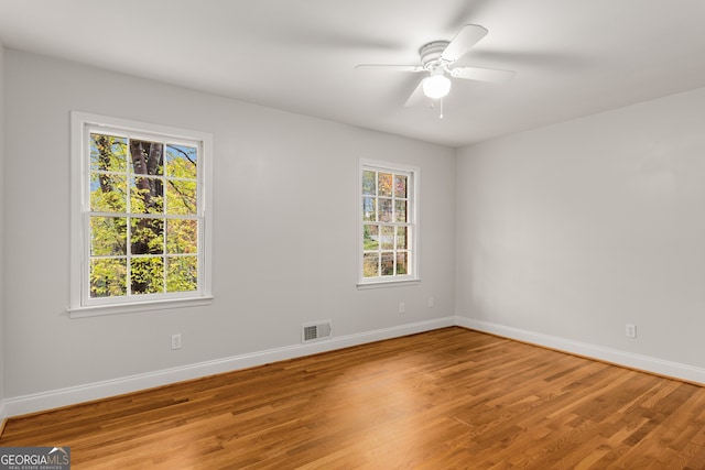 empty room featuring hardwood / wood-style floors, a wealth of natural light, and ceiling fan