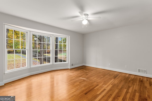 spare room with ceiling fan, a healthy amount of sunlight, and light hardwood / wood-style floors