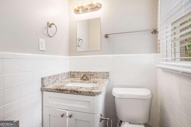 bathroom with vanity, toilet, and tile walls