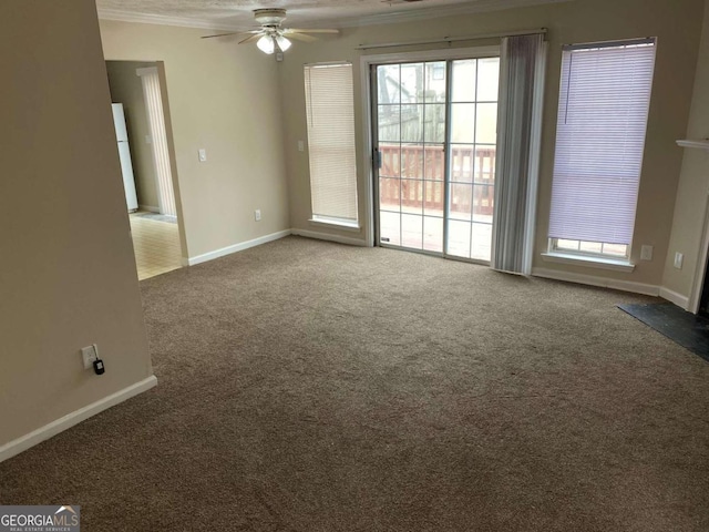 spare room featuring dark colored carpet, ceiling fan, and crown molding