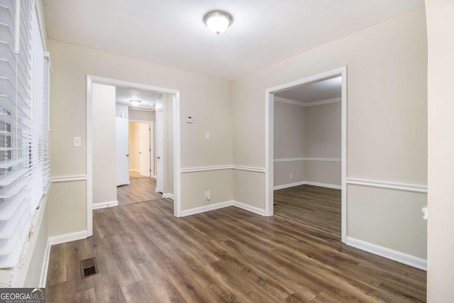 empty room featuring dark wood-type flooring and ornamental molding