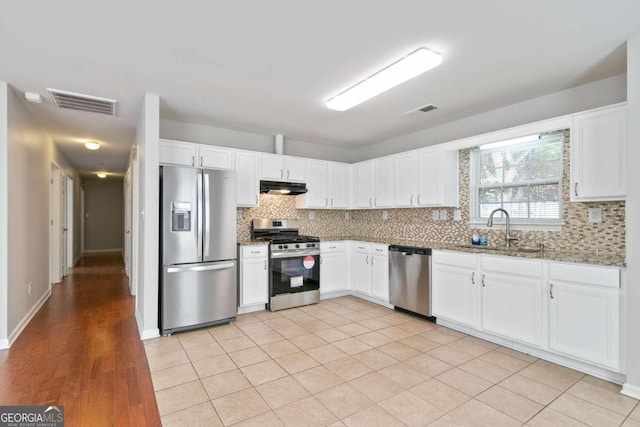 kitchen with light stone counters, decorative backsplash, sink, white cabinetry, and appliances with stainless steel finishes