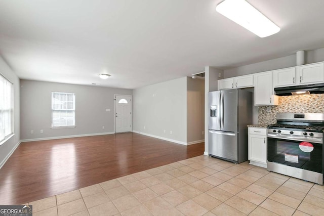 kitchen with white cabinets, decorative backsplash, light hardwood / wood-style floors, and stainless steel appliances