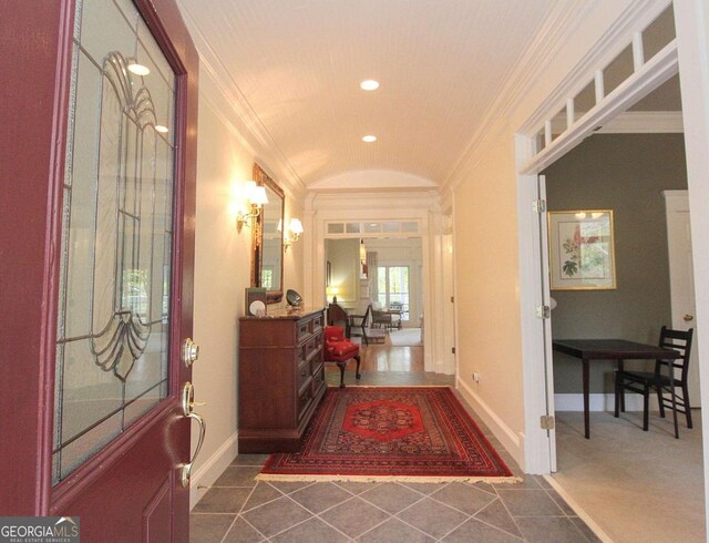 entryway featuring dark tile patterned floors, lofted ceiling, and ornamental molding