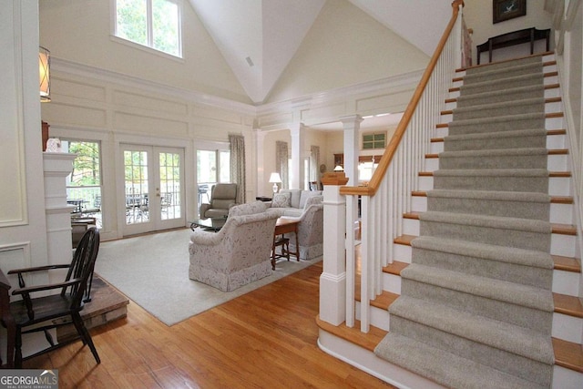 living room with french doors, ornate columns, high vaulted ceiling, and wood-type flooring