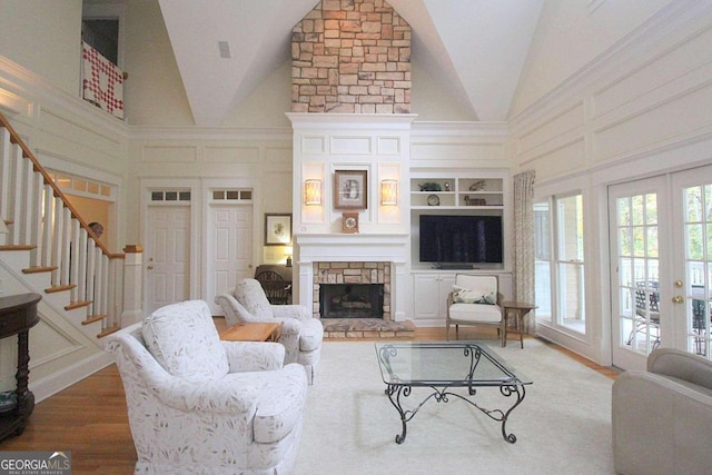 living room featuring high vaulted ceiling, a stone fireplace, wood-type flooring, and french doors