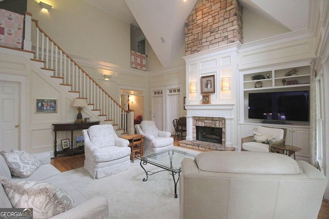 living room with a stone fireplace, built in features, light hardwood / wood-style flooring, and high vaulted ceiling