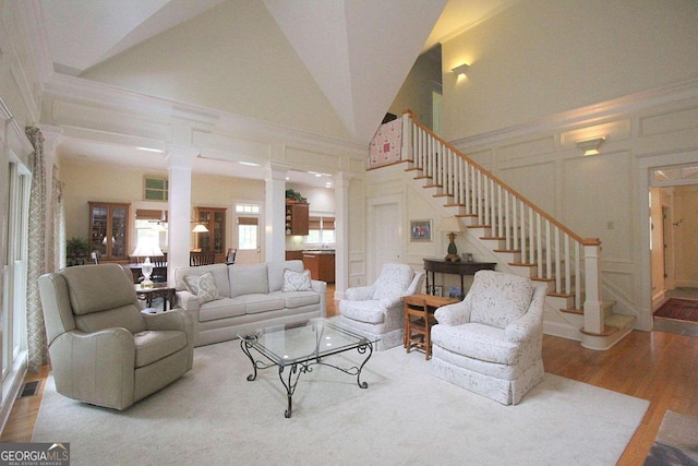 living room with high vaulted ceiling, hardwood / wood-style floors, and ornate columns