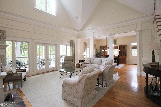 living room featuring light hardwood / wood-style floors, french doors, a healthy amount of sunlight, and high vaulted ceiling