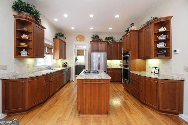 kitchen with crown molding, light wood-type flooring, appliances with stainless steel finishes, and a center island