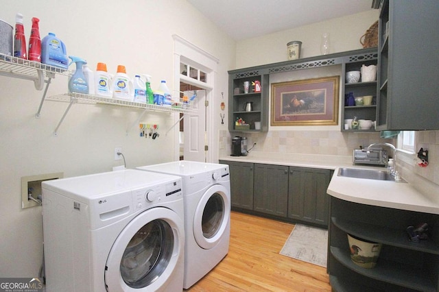 washroom with washer and clothes dryer, light wood-type flooring, cabinets, and sink