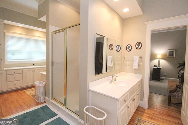 bathroom with vanity, hardwood / wood-style flooring, ornamental molding, and a shower with shower door