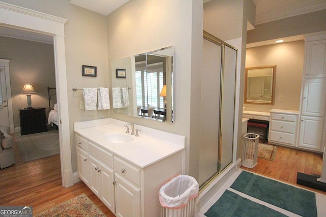 bathroom featuring vanity, hardwood / wood-style flooring, a shower with door, and crown molding