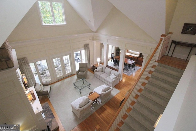 living room with french doors, high vaulted ceiling, hardwood / wood-style floors, and decorative columns