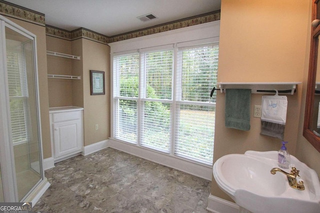 bathroom featuring a shower with shower door and sink