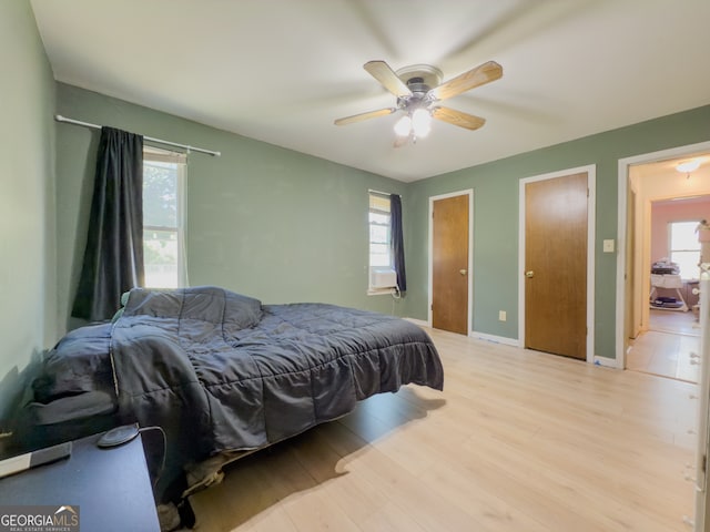 bedroom featuring ceiling fan, light hardwood / wood-style flooring, and multiple windows