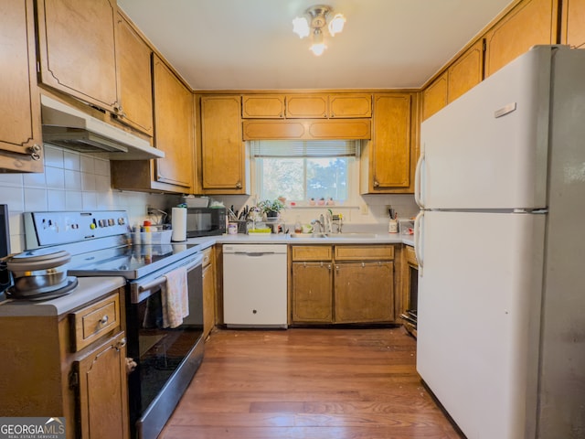 kitchen featuring decorative backsplash, sink, wood-type flooring, and white appliances