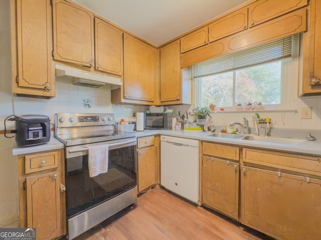 kitchen with decorative backsplash, light wood-type flooring, white dishwasher, sink, and stainless steel range with electric cooktop