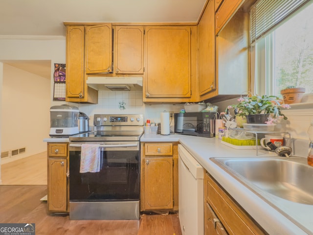 kitchen with light wood-type flooring, tasteful backsplash, white dishwasher, sink, and electric range