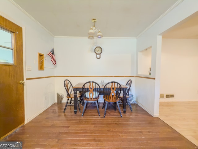 dining space featuring hardwood / wood-style flooring, an inviting chandelier, and crown molding