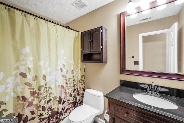 bathroom with vanity, toilet, and a textured ceiling