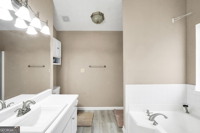 bathroom with vanity, wood-type flooring, and a tub to relax in