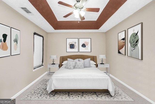 bedroom featuring ceiling fan, a tray ceiling, and carpet floors