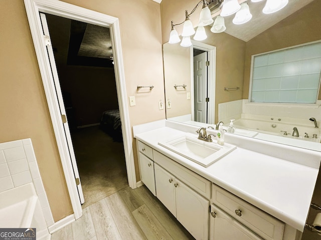 bathroom featuring hardwood / wood-style floors, a washtub, vanity, and vaulted ceiling