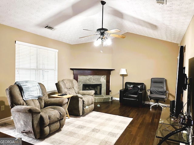 living room with lofted ceiling, a textured ceiling, hardwood / wood-style flooring, ceiling fan, and a fireplace