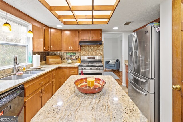 kitchen with stainless steel appliances, sink, backsplash, hanging light fixtures, and hardwood / wood-style floors