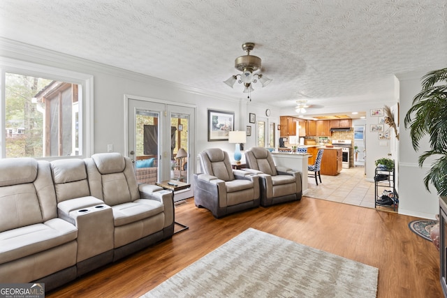 living room with light hardwood / wood-style floors, ceiling fan, a textured ceiling, and crown molding