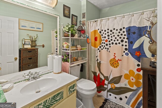 bathroom with tile patterned floors, vanity, a textured ceiling, and toilet