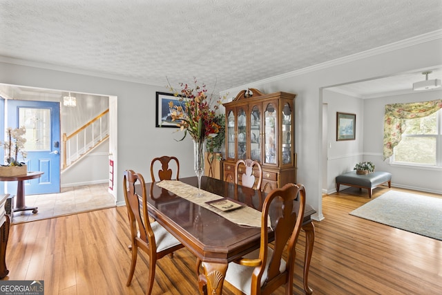 dining area with ornamental molding, light hardwood / wood-style floors, a notable chandelier, and a textured ceiling