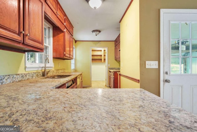 kitchen with sink, light stone counters, and a healthy amount of sunlight