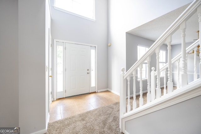 tiled entrance foyer featuring a towering ceiling, a healthy amount of sunlight, and a textured ceiling