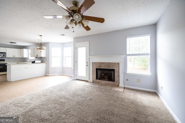 unfurnished living room featuring a wealth of natural light, light colored carpet, a textured ceiling, and ceiling fan