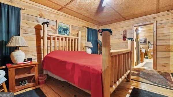 bedroom featuring ceiling fan, wood walls, and wood-type flooring