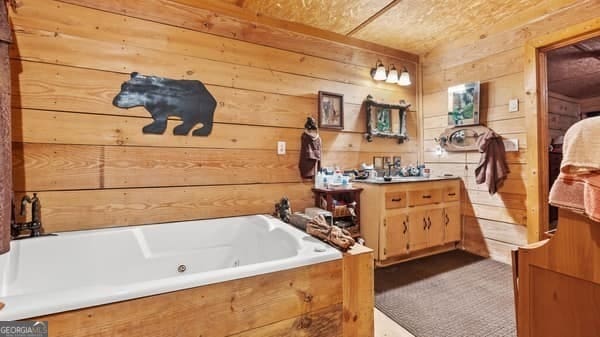 bathroom with vanity, a bathtub, and wood walls